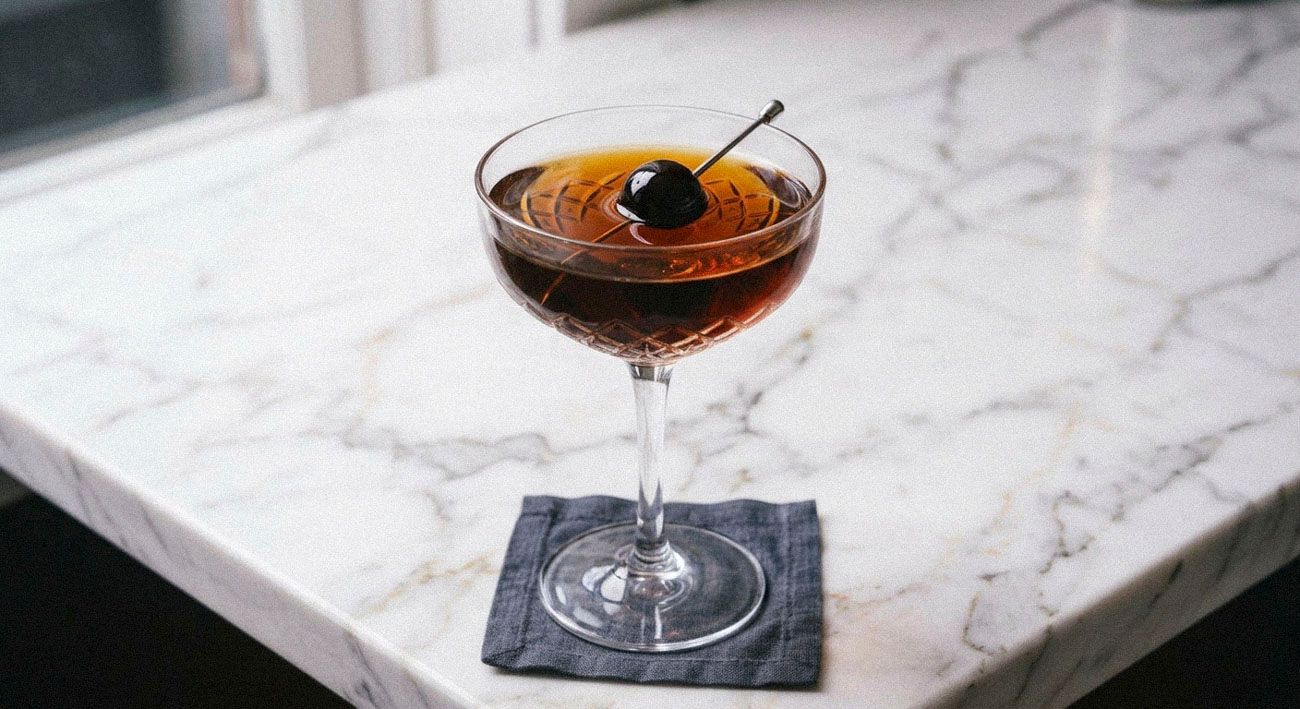 black manhattan in a coupe glass on marble counter